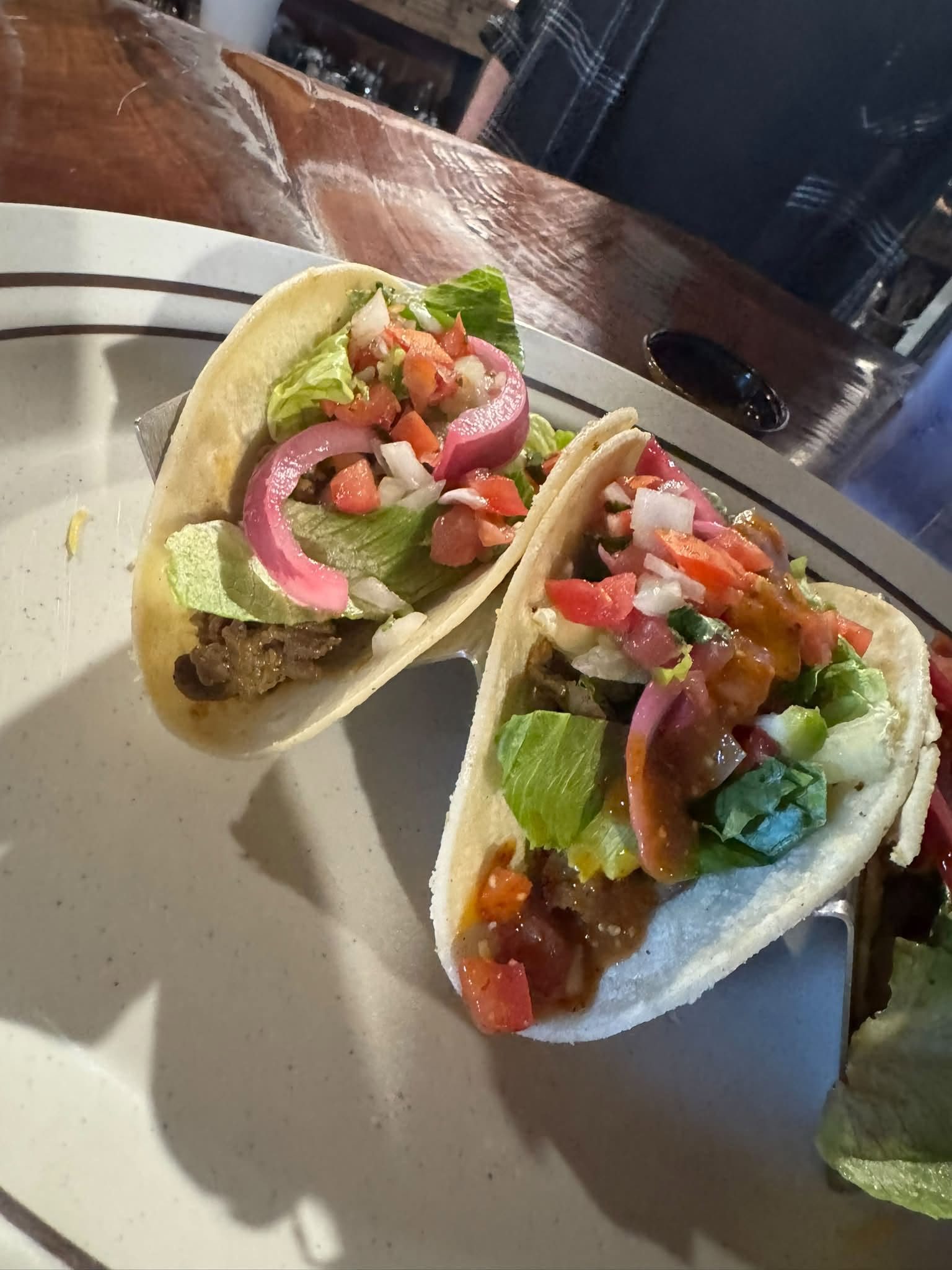 Two street tacos with pico de gallo and pickled onion